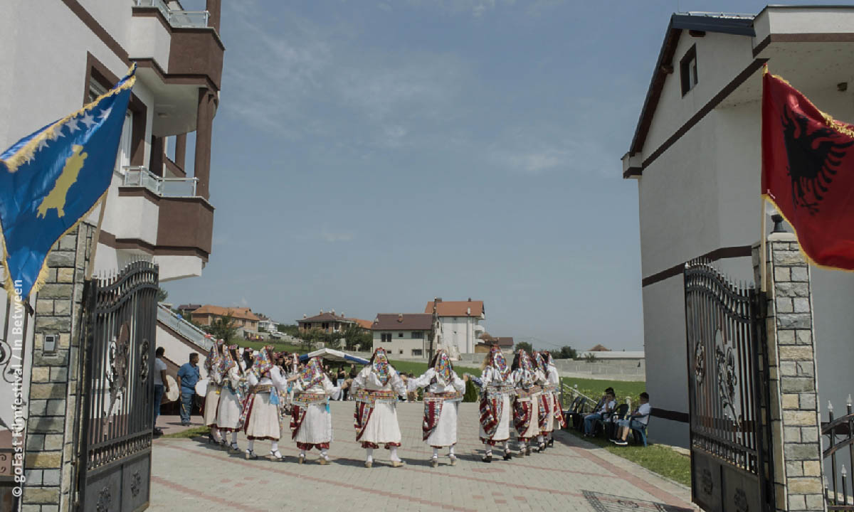 Filmstill aus "In Between": Bild von traditonellem Gruppentanz auf einem Hof (© goEast Filmfestival / In Between)