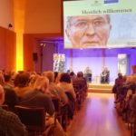Zuschauer in einem Veranstaltungsaal mit Fachpanel