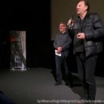 Zwei Männer mit Mikrofon vor einer Kinoleinwand