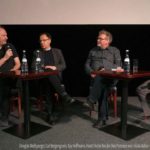 Menschen sitzen als Panel vor einer Kinoleinwand