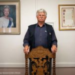 Mann neben Portrait von Königin Elizabeth II