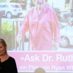 Bild von Frau mit Mikrofon vor Leinwand