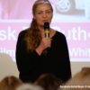 Bild von Frau mit Mikrofon vor Leinwand