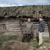 Zwei Männer vor einer Holzhütte