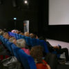Publikum und Mann vor der Leinwand
