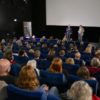 Ansicht des Publikums von hinten und Leinwand