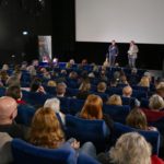 Ansicht des Publikums von hinten und Leinwand