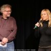 Frau und Mann mit Mikrofon vor einer Kinoleinwand