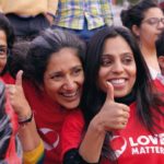 Mehrere Frauen in roten T-Shirts geben ein Thumbs Up
