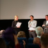 Bild von drei Personen vor einer Leinwand