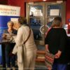 Bild mehrerer Personen vor Plakaten im Foyer