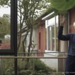Mann vor einem Fenster spielt mit einem Ballon