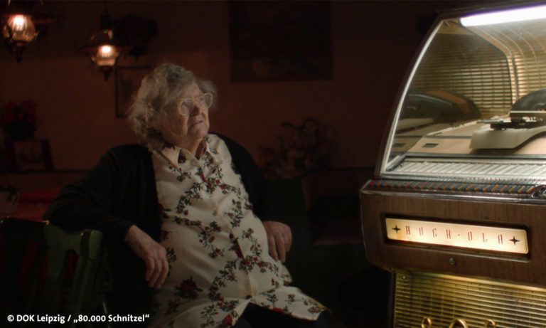 Filmstill "80.000 Schnitzel", abgebildet ist eine alte Frau vor einer Jukebox (Foto: DOK Leipzig/"80.000 Schnitzel")