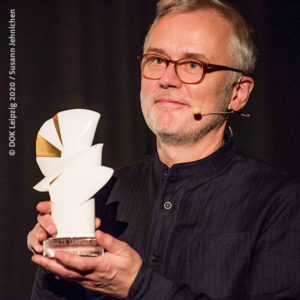 Bild: Festivallleiter Christoph Terhechte hält Goldene Taube beim DOK Leipzig (Foto: Susann Jennichen/DOK Leipzig)