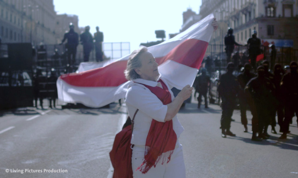 Filmstill aus „Courage“ von Aliaksei Paluyan; man sieht eine demonstrierende Frau mit Fahne (Foto: Living Pictures Production)