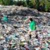 Frau läuft auf Plastikmüllberg