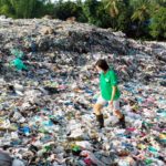 Frau läuft auf Plastikmüllberg