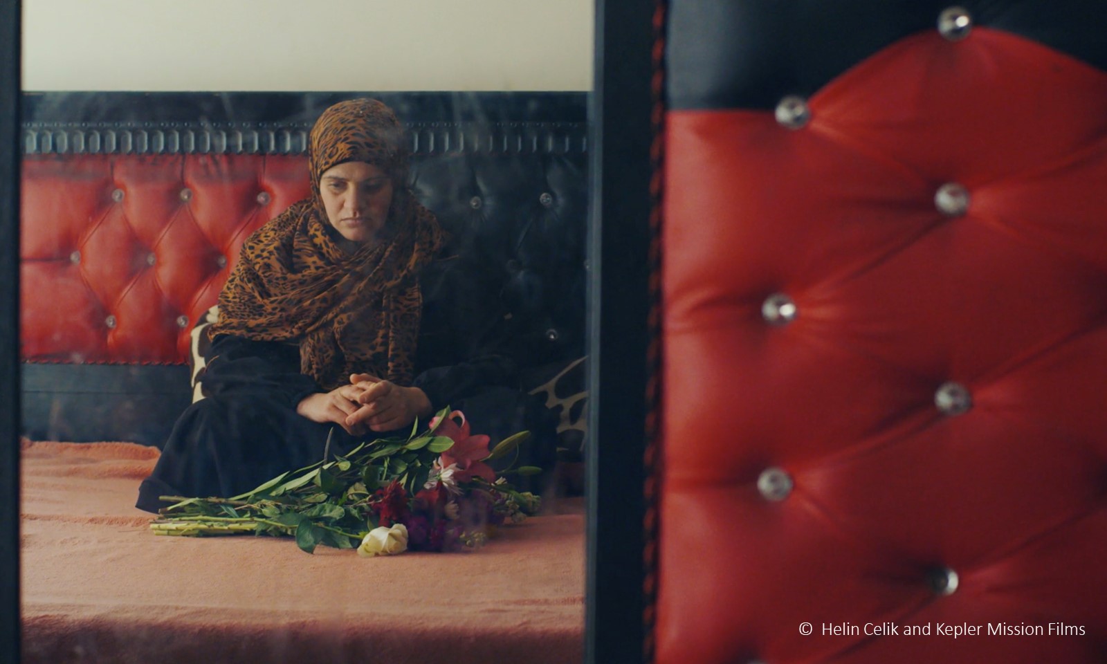 Protagonistin von „Anqa“ von Helin Çelik sitzt vor einem Blumenstraß.