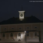 Filmstill aus DIE KINDER AUS KORNTAL. Man sieht eine Kirche im Abendlicht, im Vordergrund fährt ein Kind auf einem Roller durchs Halbdunkel (Credit: DOK Leipzig 2023/DIE KINDER AUS KORNTAL, Regie: Julia Charakter)