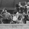 Leni Riefenstahl bei der Kamera, während der Dreharbeiten von „Olympia“ mit Joseph Goebbels und Hermann Göring auf der Tribüne (1936) (aus dem Nachlass)